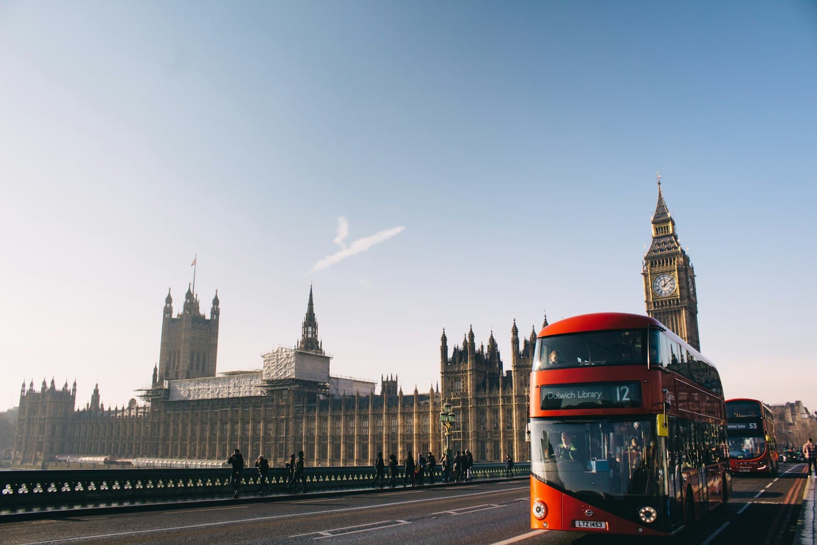 Red double-decker bus passing the Palace of Westminster and Big Ben in London